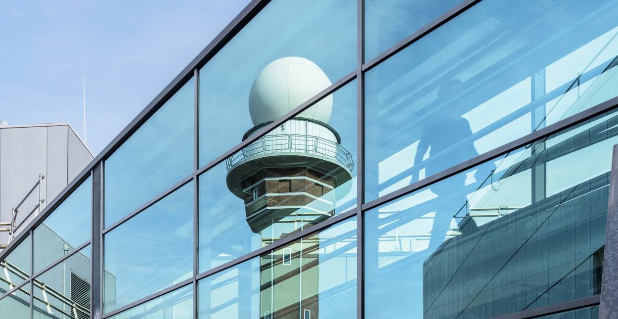 Radar tower reflects in the glass KNMI building